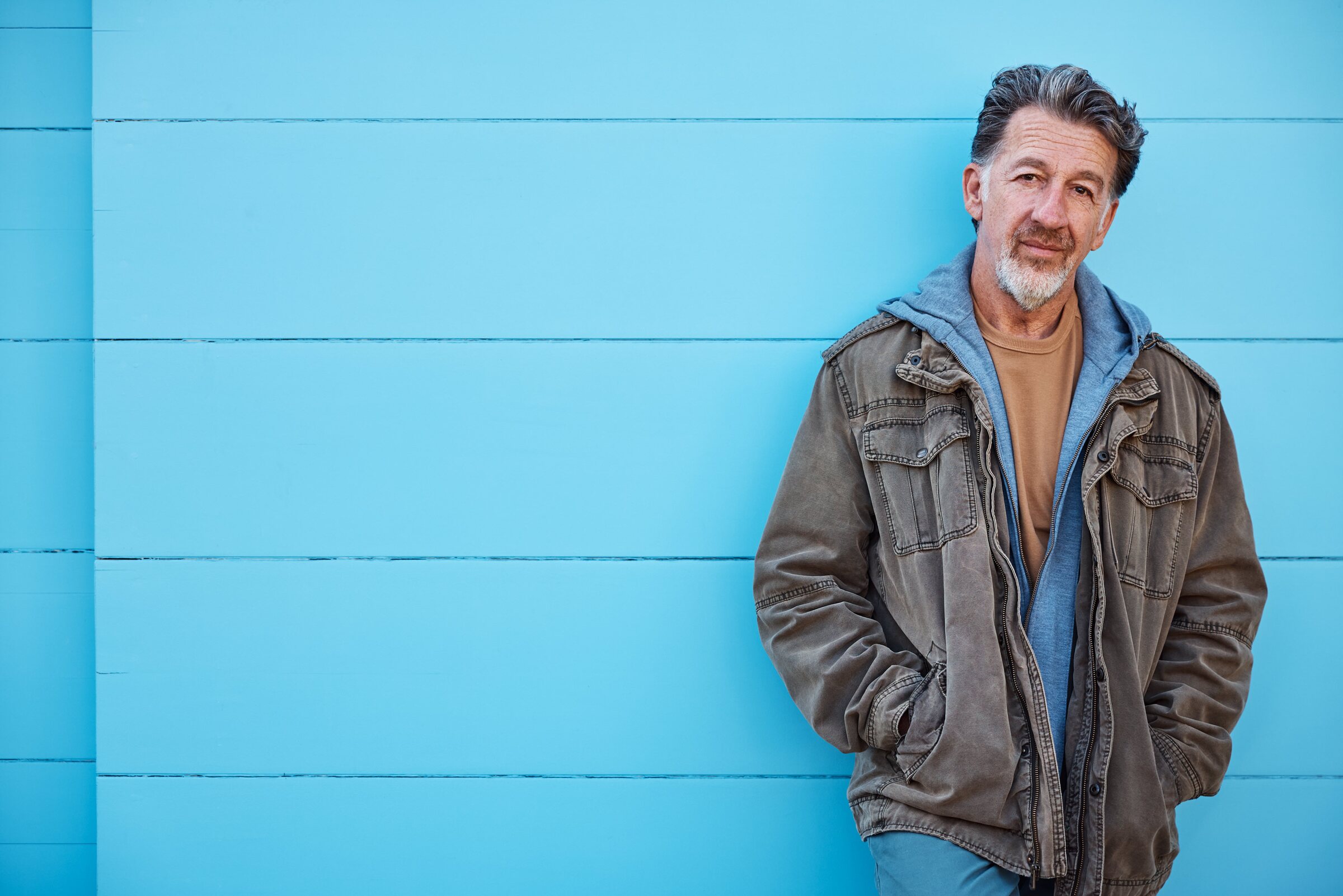 Djilali Rez-Kallah in an olive utility jacket against a blue wall